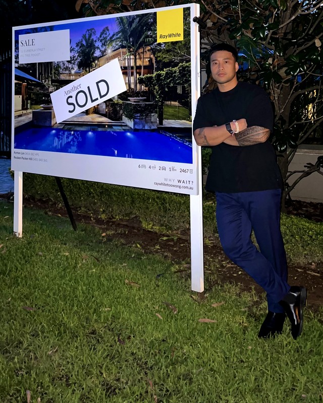 Ayrton Dela Cruz Lim standing beside a Ray White SOLD sign
